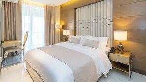 Una habitación de hotel moderna con una cama grande, lámparas de noche, un escritorio y una silla.