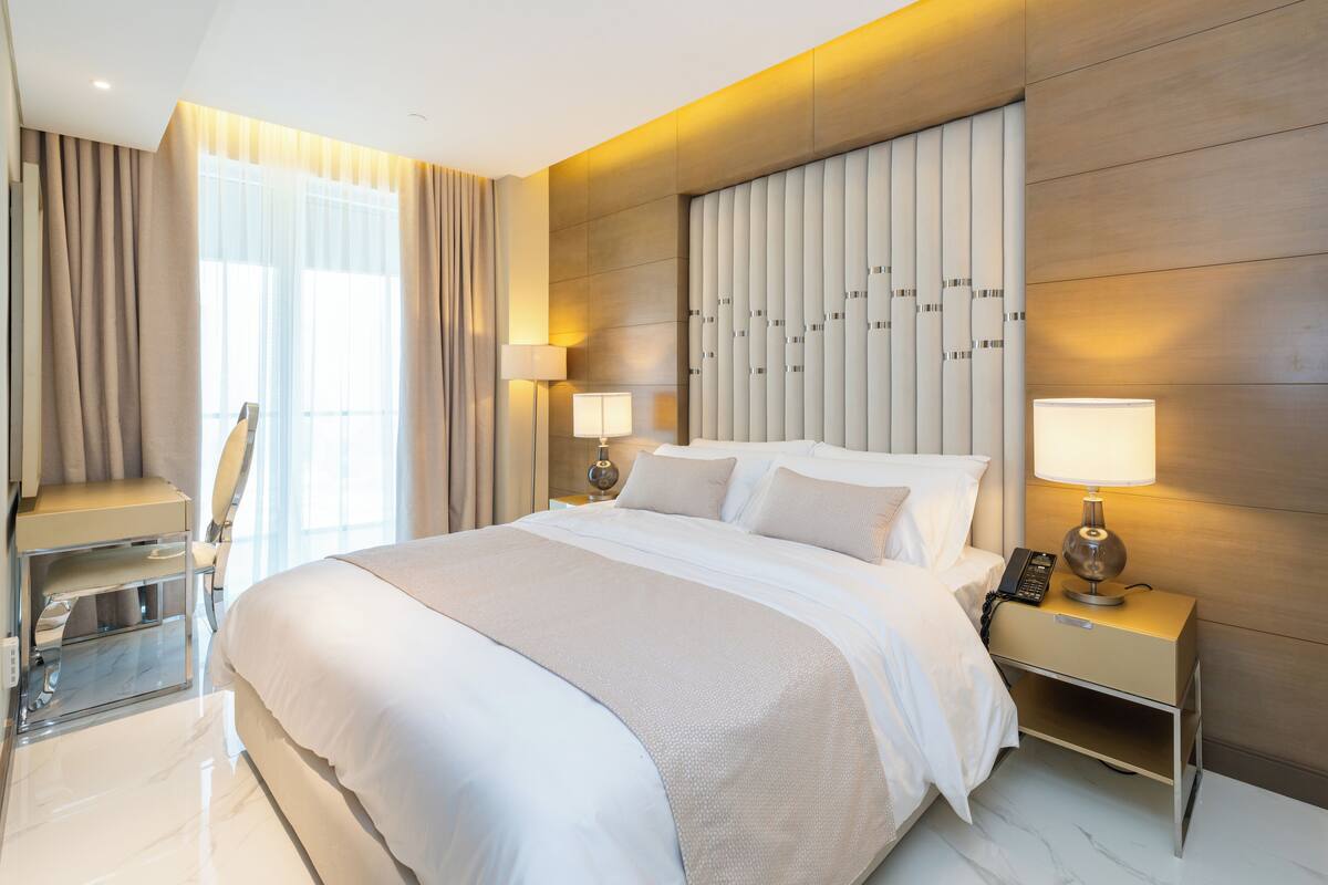 Une chambre d’hôtel moderne avec un grand lit, des lampes de chevet, un bureau et une chaise.