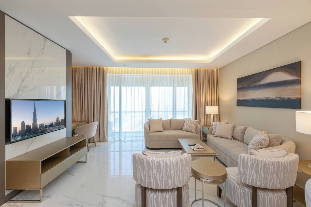 Une chambre d’hôtel moderne équipée d’un grand téléviseur à écran plat, d’un canapé, d’une table basse et d’un meuble pour la télévision.