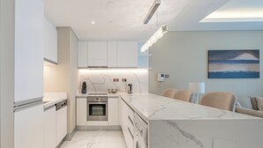 Una cocina moderna con armarios blancos, encimera de mármol y electrodomésticos integrados.