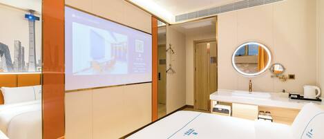 A hotel room with a bed, a large mirror, a sink, and a projection screen displaying a cityscape.
