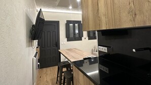 Une cuisine compacte avec des meubles en bois, un plan de travail noir et une cuisinière intégrée.