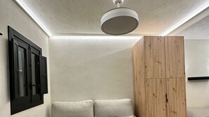 Une pièce moderne et minimaliste, avec un canapé beige, une armoire en bois et un luminaire au plafond.