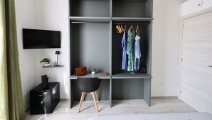 A modern room with a grey wardrobe, a flat-screen TV, a desk with a chair, and a bed. - LEVANZO Standard room with small private patio (Favignana)