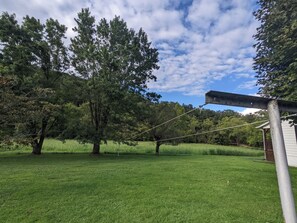 Un espacio cubierto de césped con árboles y una estructura metálica.