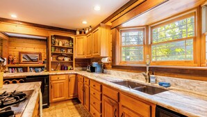 A wooden kitchen with a large window, a sink, and a stove. - Escape to our cozy lakeview cabin with modern amenities, spacious decks and serene surroundinngs. (Radford)