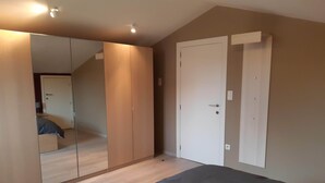 Ein Schlafzimmer mit Bett, Kleiderschrank, Spiegel und einer Tür.