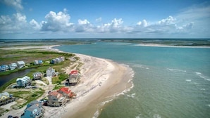 Une vue aérienne d’une zone côtière avec une plage, des maisons et un ciel dégagé.