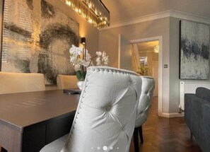 A modern dining area with a dark wood table, a tufted leather chair, and a vase of white flowers.