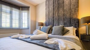 Una cama bien tendida con toallas, un cabecero y lámparas de noche en una habitación de hotel.