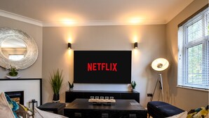 Una sala de estar moderna con un televisor de pantalla plana montado en la pared mostrando 