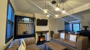 A cozy living room with leather sofas, a fireplace, and a dining area with a view. - Greta House - Luxury refurbished accommodation (Central Keswick)