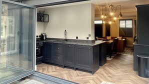 A modern kitchen with dark cabinetry, a large island, and a herringbone wood floor. - Greta House - Luxury refurbished accommodation (Central Keswick)