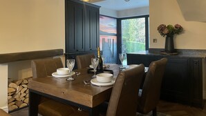 A dining area with a wooden table set for four, dark cabinets, and a view of a dock through a glass door. - Greta House - Luxury refurbished accommodation (Central Keswick)