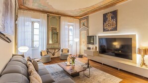 A spacious living room with a large flat-screen TV, comfortable seating, and elegant decor. - Rovelli 41 by Rent all Como (Como)