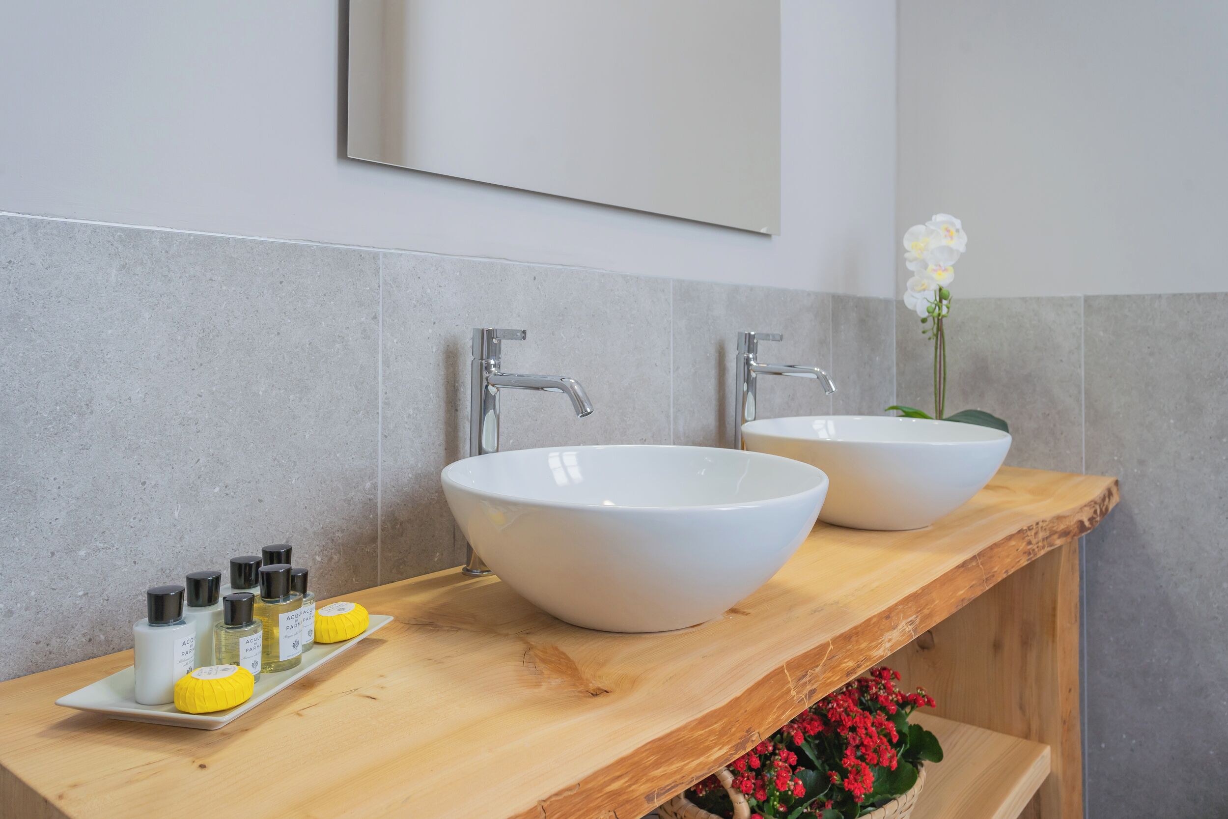 A bathroom with two white sinks, a wooden countertop, and a mirror above.