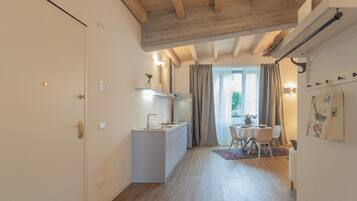 Una cocina moderna con una isla central, un comedor con mesa y sillas, y vistas al exterior a través de amplias ventanas.