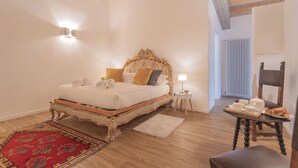 Une chambre à coucher avec un lit en bois, un tapis rouge, une petite table avec une lampe et une chaise.