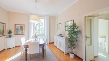 Une salle à manger avec une table en bois, des chaises blanches, un buffet blanc et une plante en pot.