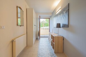 A hallway with a radiator, a mirror, a wooden console, and a door leading outside.