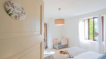 A bedroom with a crib, a bedside table with a tray of food, and a window with curtains.