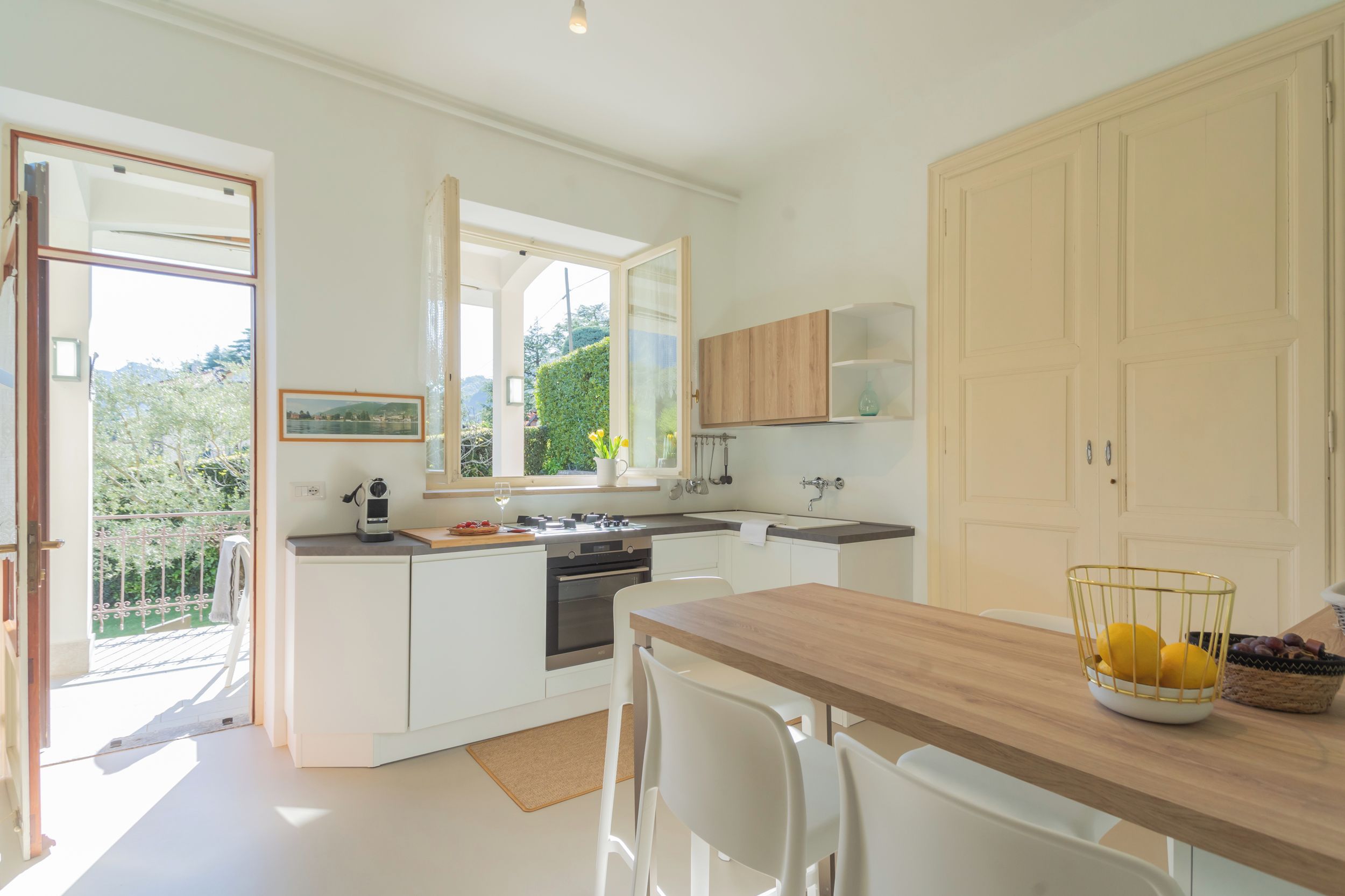 Une cuisine moderne avec des meubles blancs, un plan de travail en bois et un coin repas comprenant une table et des chaises.