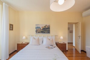 Ein Hotelzimmer mit einem Bett, zwei Nachttischen, einer Lampe, einem Bild an der Wand und einer Tür zu einem anderen Raum.