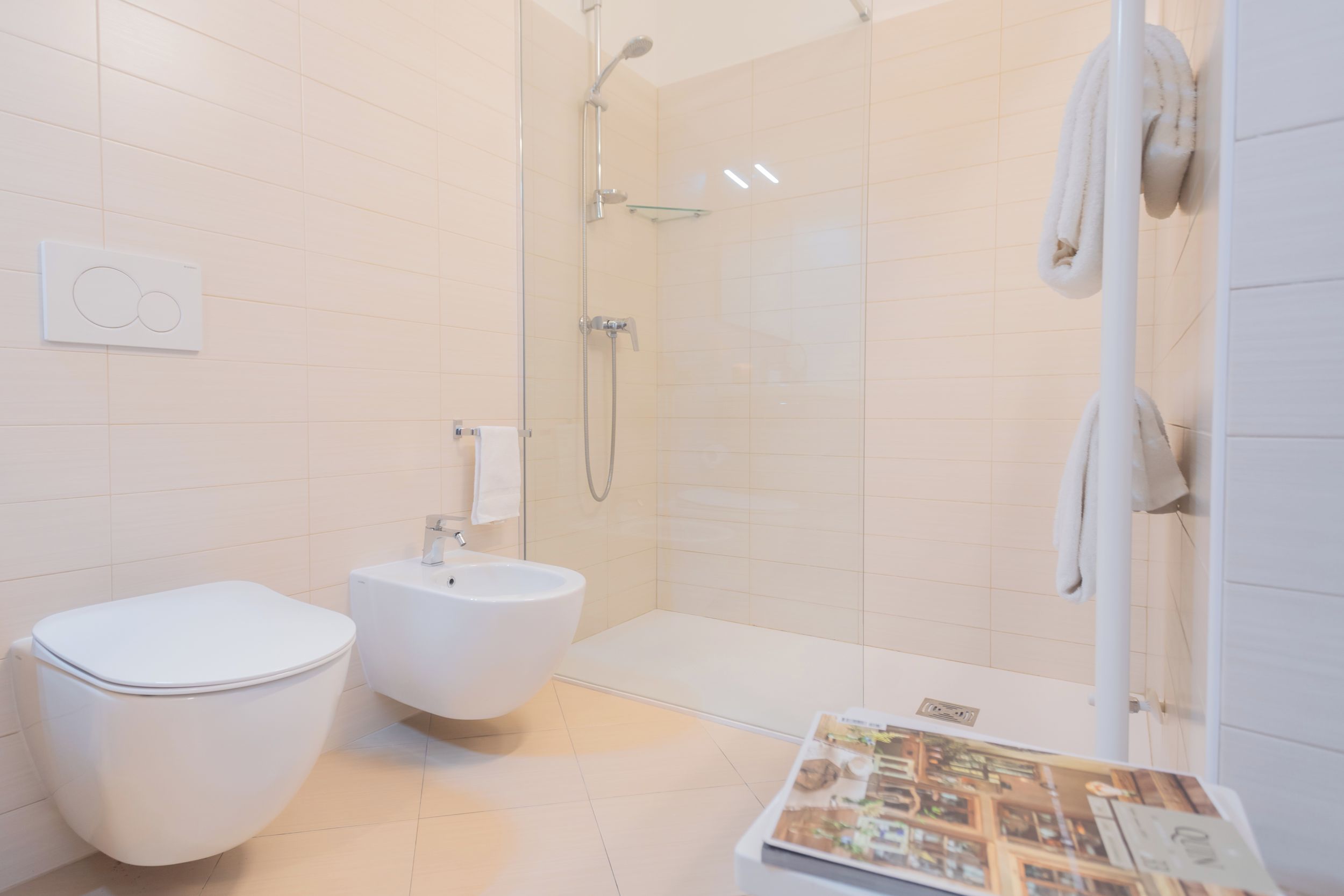 Une salle de bain moderne équipée de toilettes, d’un bidet et d’une douche à parois de verre.