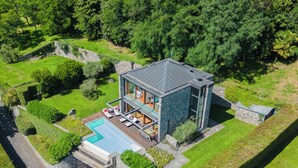 Ein modernes Haus mit Schwimmbecken, Steinaußenwand und üppiger Bepflanzung.