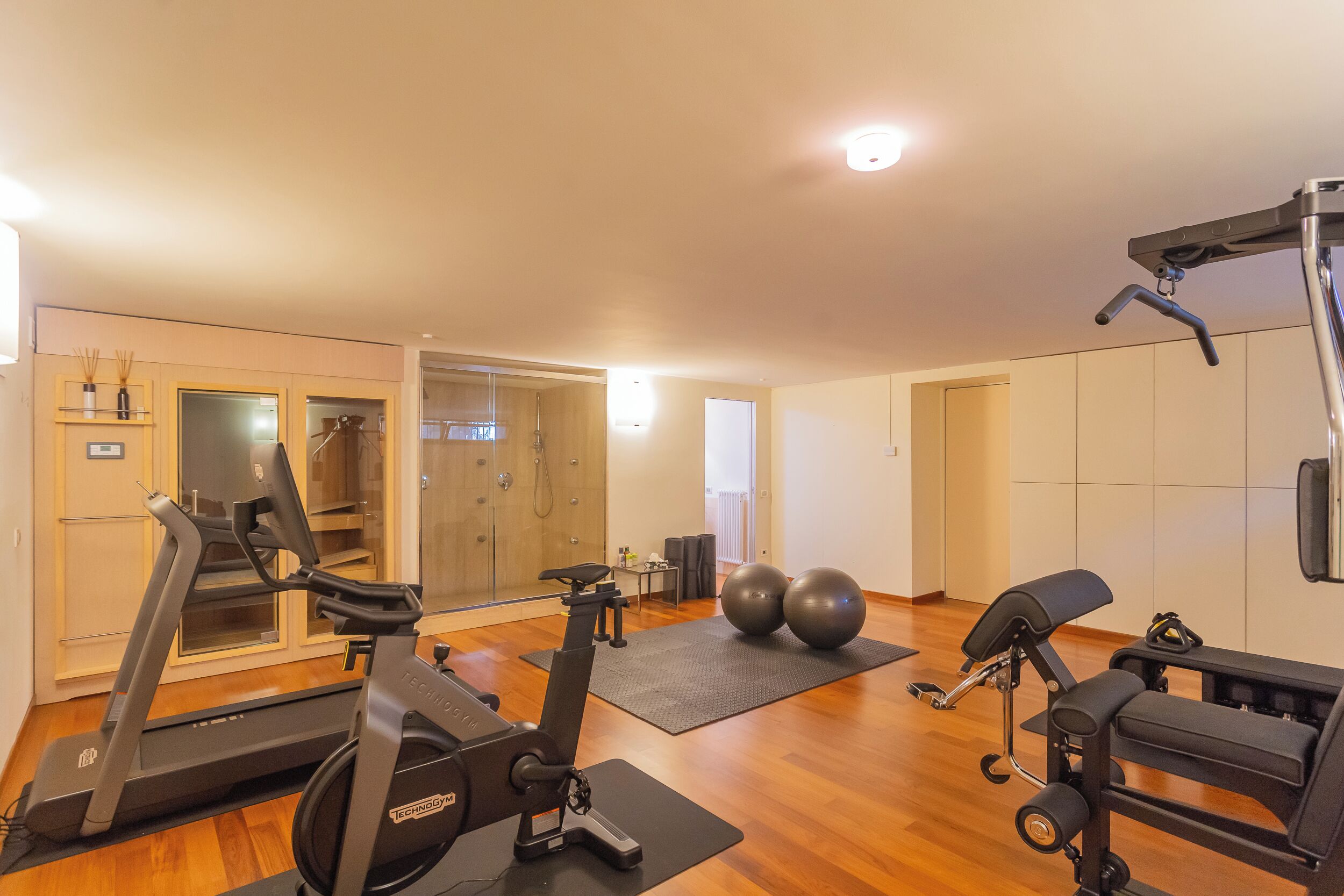 Une salle de sport à domicile équipée de matériel d’exercice, notamment un tapis de course, un vélo elliptique et un banc de musculation.