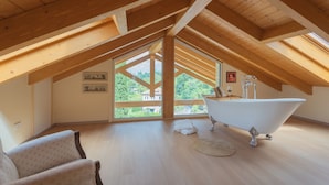 A high-ceilinged room with a skylight, a white bathtub, and a view of greenery outside. - Villa Cosima in Bellagio With Private Pool by Rent all Como (Bellagio)
