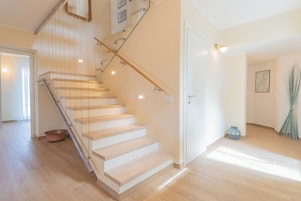 A staircase with wooden steps and glass railings, leading to an upper floor.