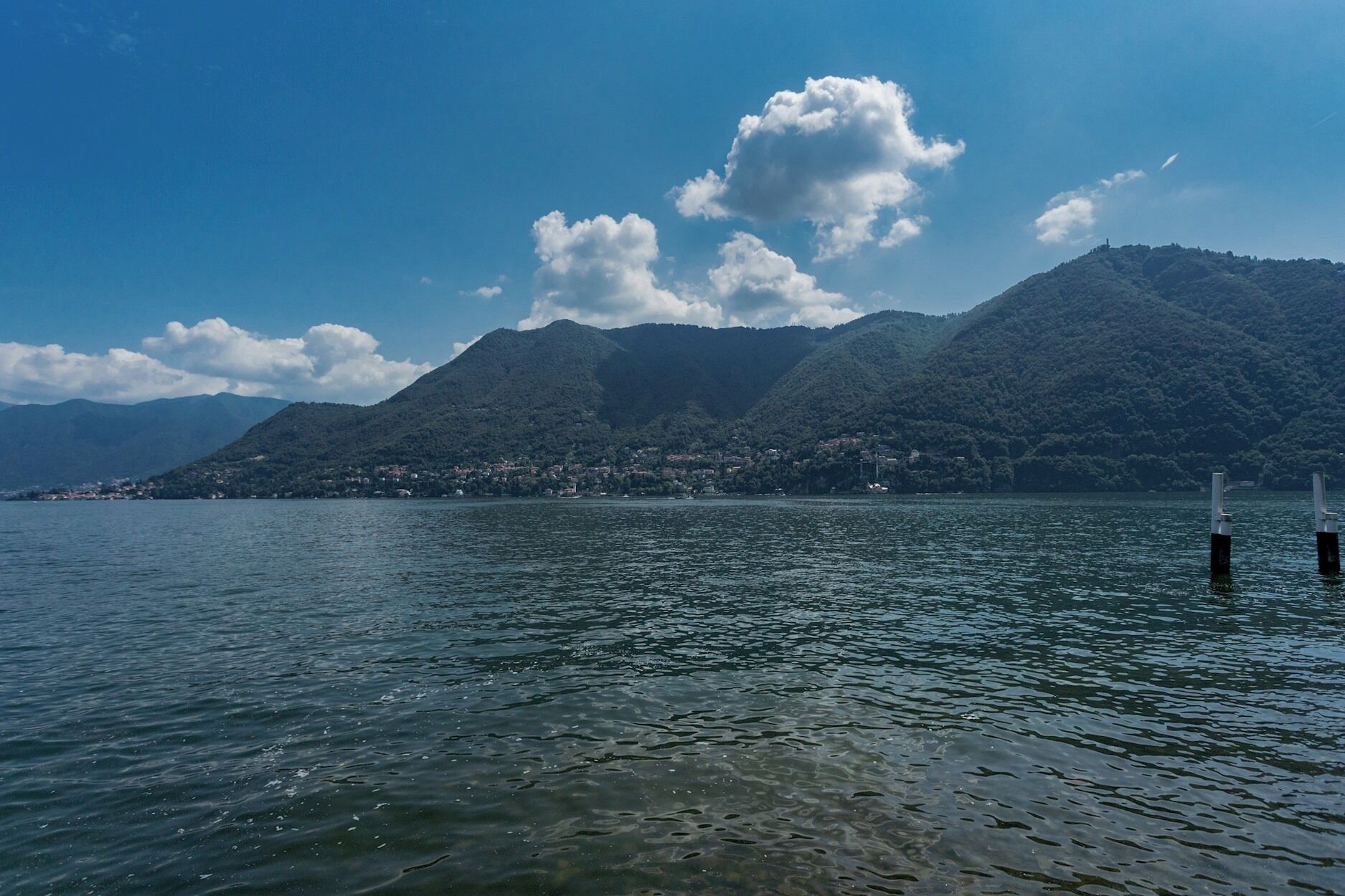 A lake with mountains in the background and a small town on the opposite shore.