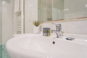 A bathroom with a white sink, a mirror, a towel rack, and a small potted plant. - Black Loft Como by Rent all Como (Como)