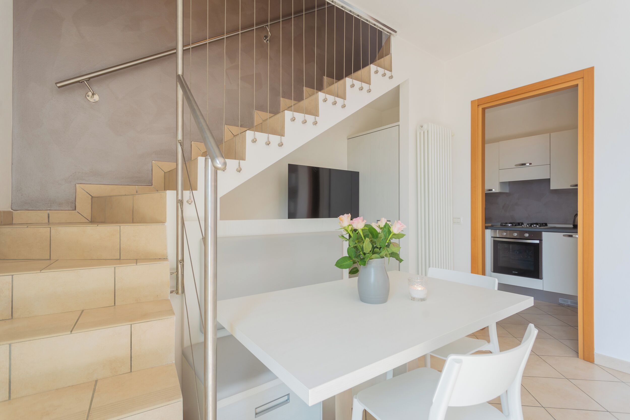 Une cuisine moderne avec des meubles blancs, une cuisinière et un coin repas comprenant une table et des chaises.