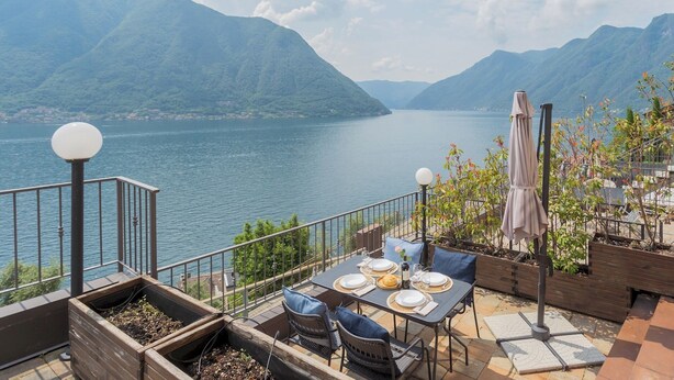 An outdoor dining area with a view of a lake and mountains.
