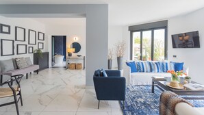 Ein modernes Wohnzimmer mit einer Couch, Sesseln, einem Couchtisch und einem großen Fenster.