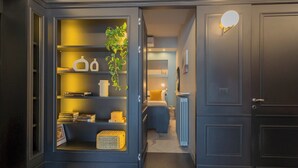 Ein modernes Interieur mit einem dunkel gestalteten Raum, der ein Einbaubuchregal, eine Zimmerpflanze und ein Bett mit Nachtschränkchen zeigt.