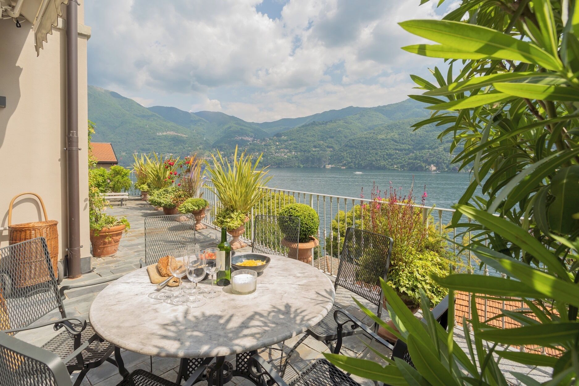 A terrace with a round table, chairs, and potted plants.