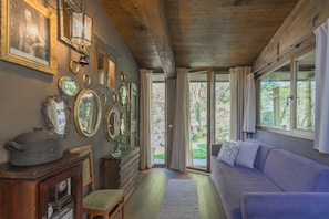 A cozy room with a wooden ceiling, a purple sofa, and a wall adorned with framed mirrors and a vintage clock. - The Writer's Nest by Rent all Como (Faggeto Lario)