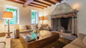 A cozy living room with a fireplace, a sofa, a coffee table, and two lamps. - Villa Riva Bellagio With Pool by Rent all Como (Bellagio)