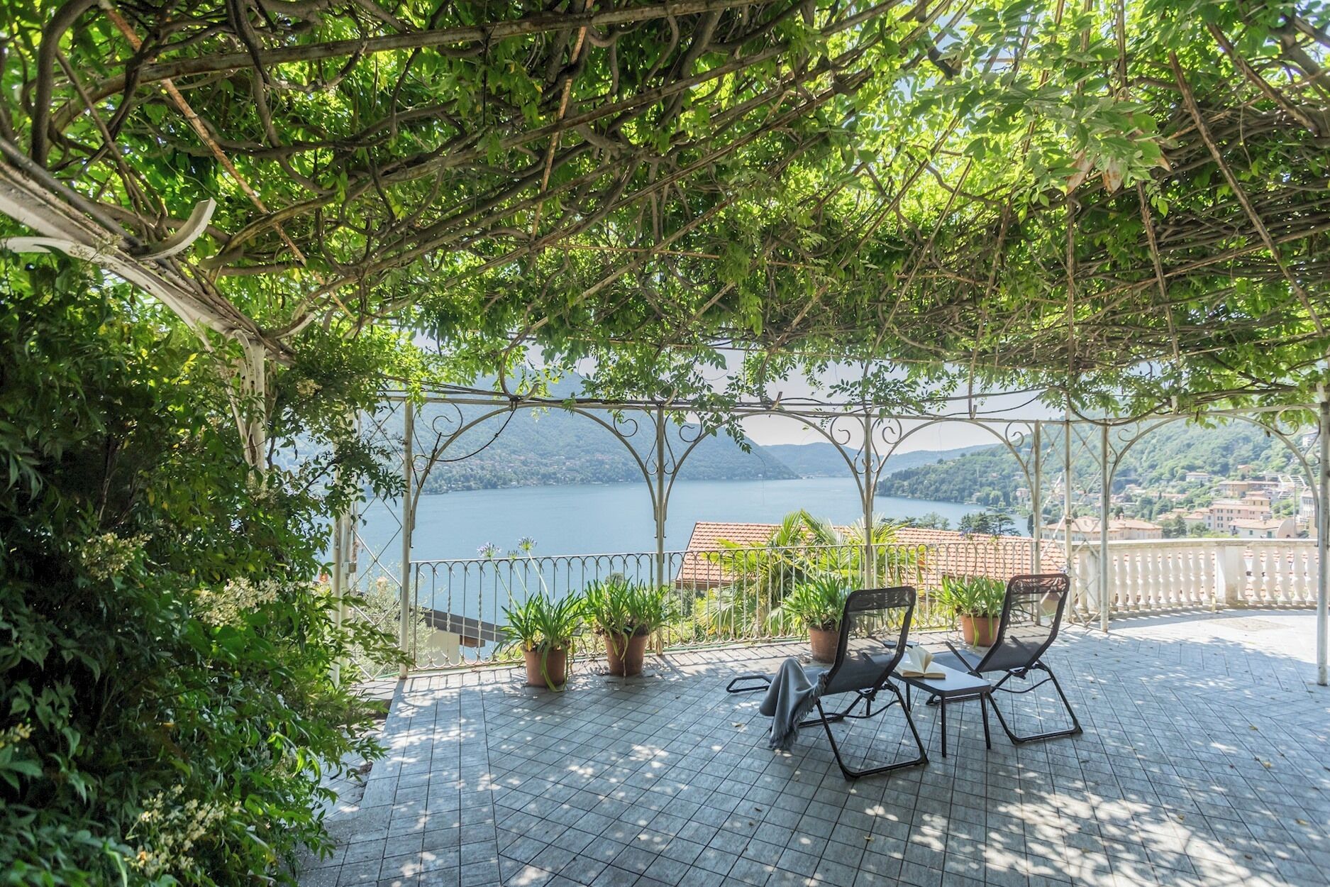 A covered outdoor seating area with a view of a lake and hills.