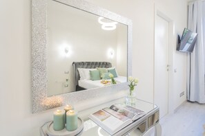 A bedroom with a large mirror, a bed with green pillows, a bedside table with candles, and a magazine. - Cernobbio Dream Suites by Rent all Como (Cernobbio)