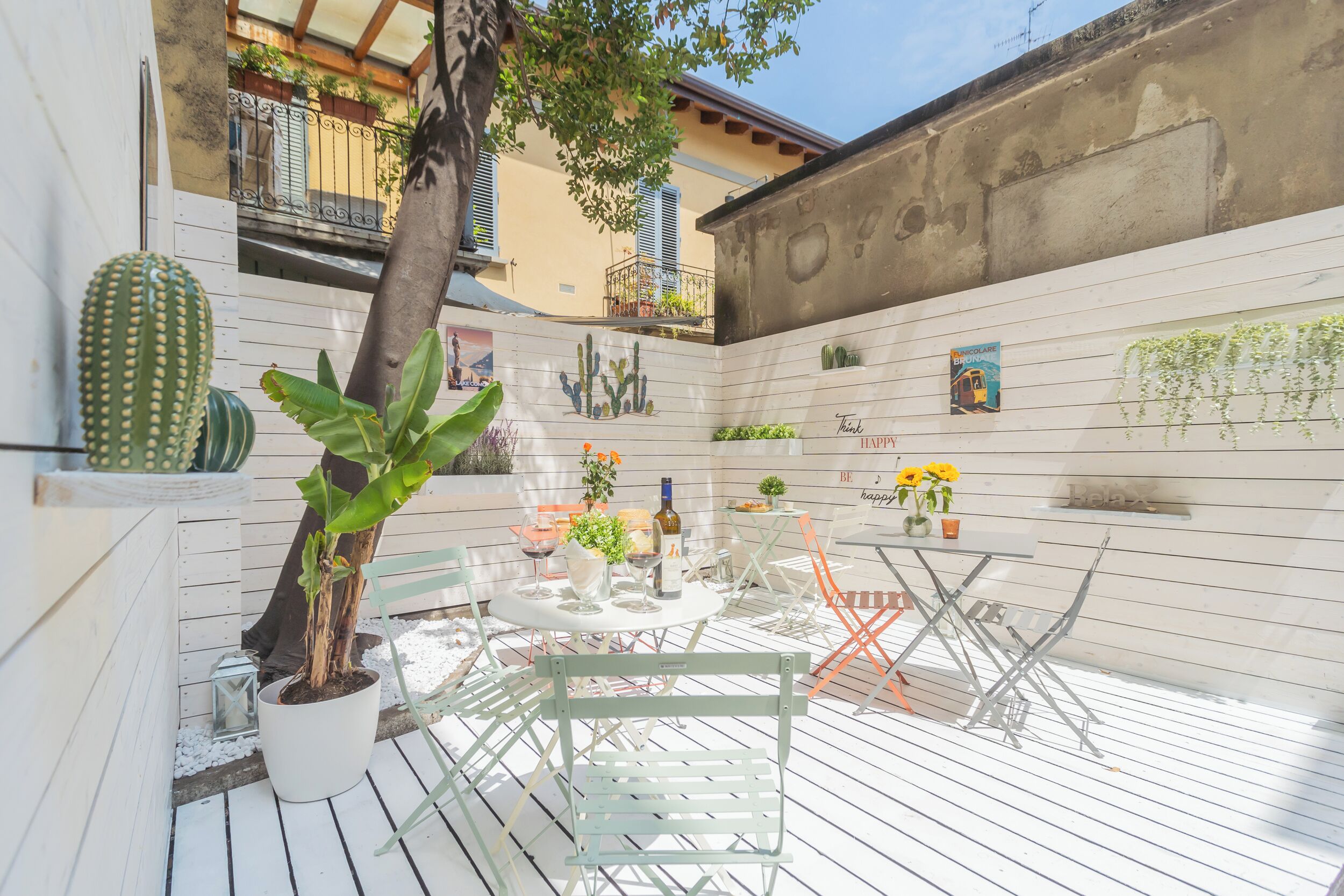 A patio with a round table, chairs, and potted plants.