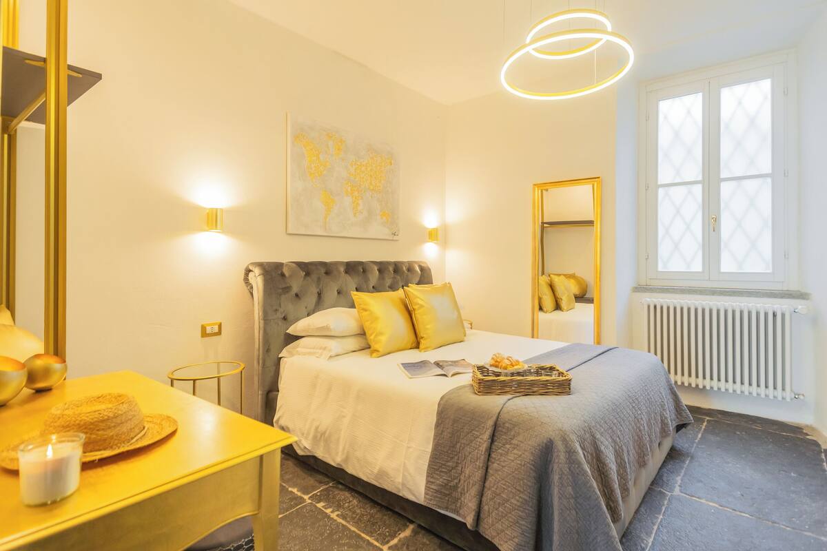Un dormitorio con cama, mesita de noche, lámpara y ventana con vistas.
