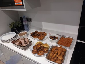 Un tavolo del buffet con diversi piatti, tra cui carne, fritture e prodotti da forno.