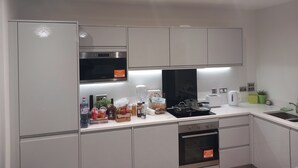A modern kitchen with white cabinets, a built-in oven, a microwave, and a sink. - Tranquil Loughton Apartment Retreat (Loughton)