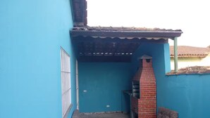 A small outdoor patio area with a brick oven, a bench, and a window with metal bars.
