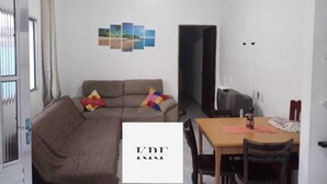 A living room with a sofa, a dining table, and a ceiling fan.