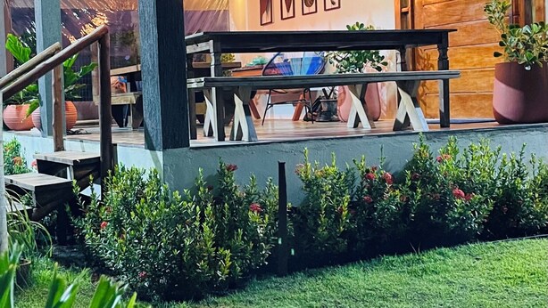 Un espace extérieur moderne aménagé avec un banc en bois, des plantes en pot et un escalier menant à un niveau supérieur.